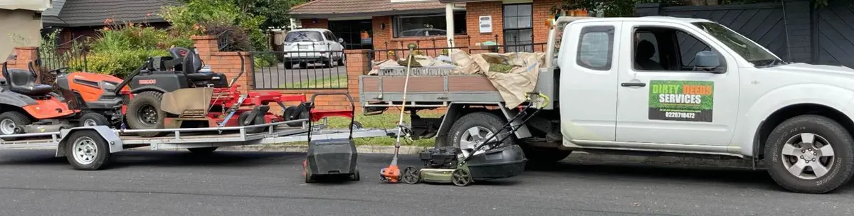 Dirty Deeds Services truck and trailer loaded with mowing equipment